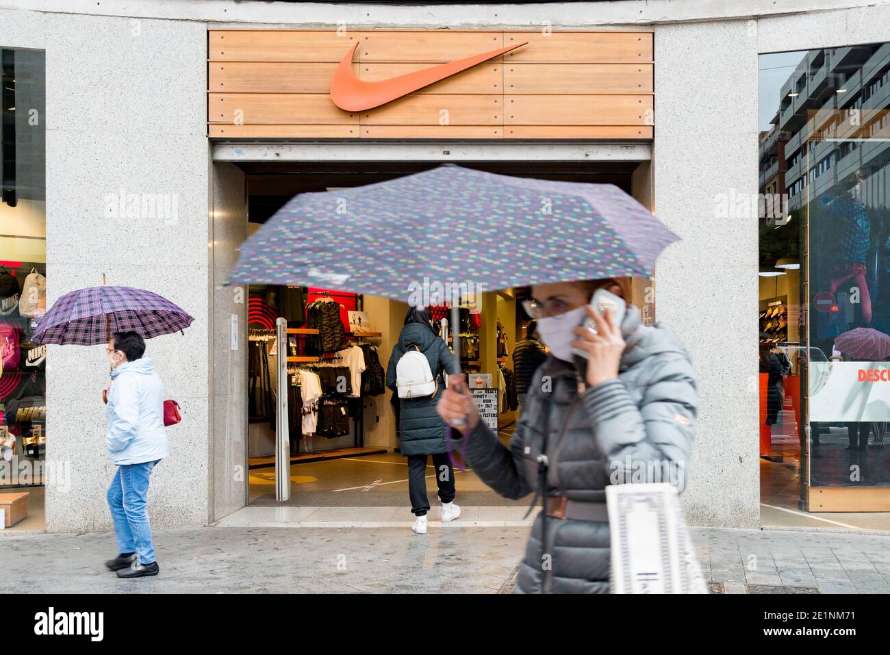 People wearing face masks walk past a Nike store during the winter sales.In  the last weeks of Christmas, the cases of Covid19 in Valencia have  increased, this has caused the winter sales
