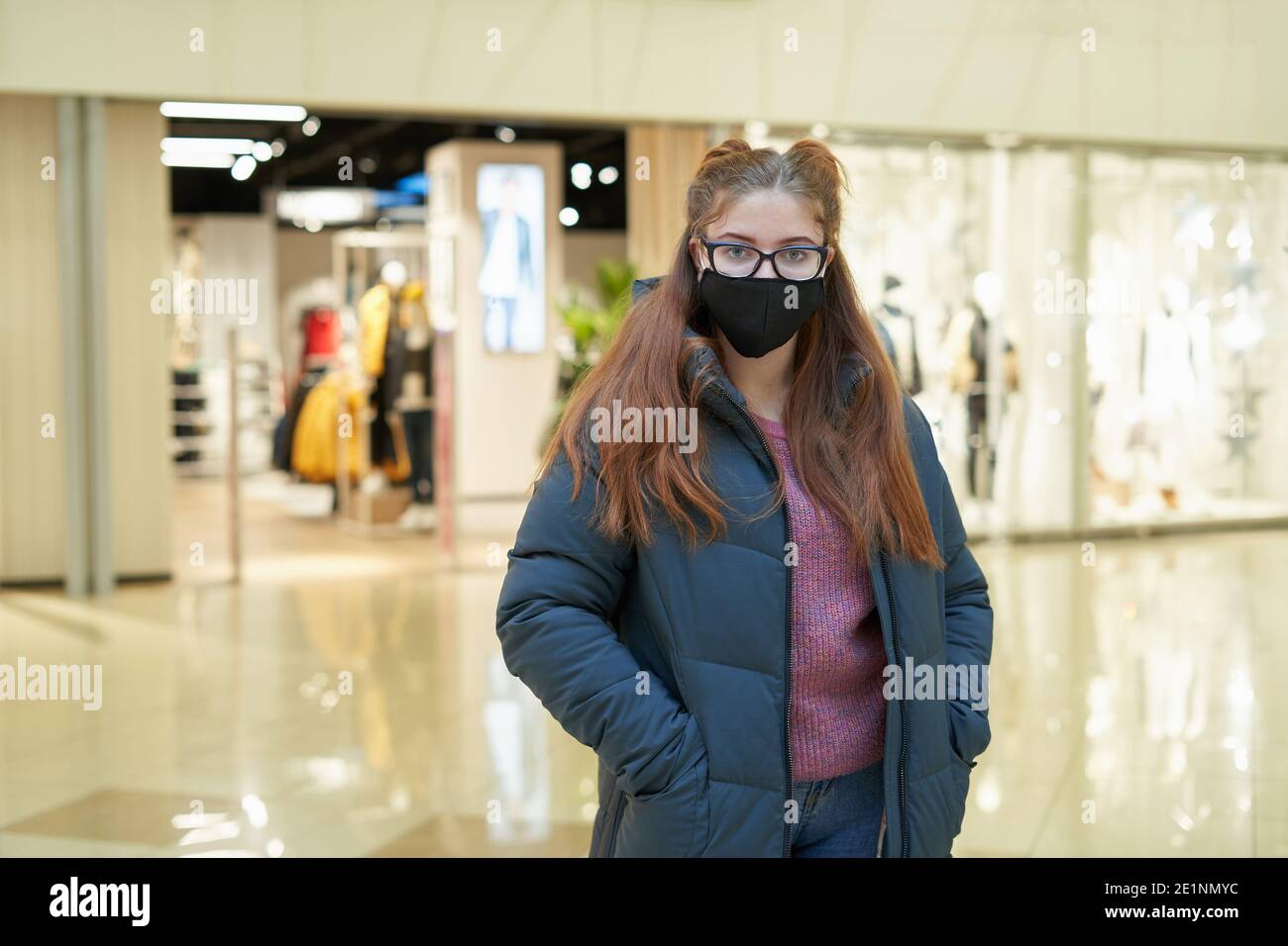 Portrait of Young woman wearing black face mask in a shopping mall Stock Photo