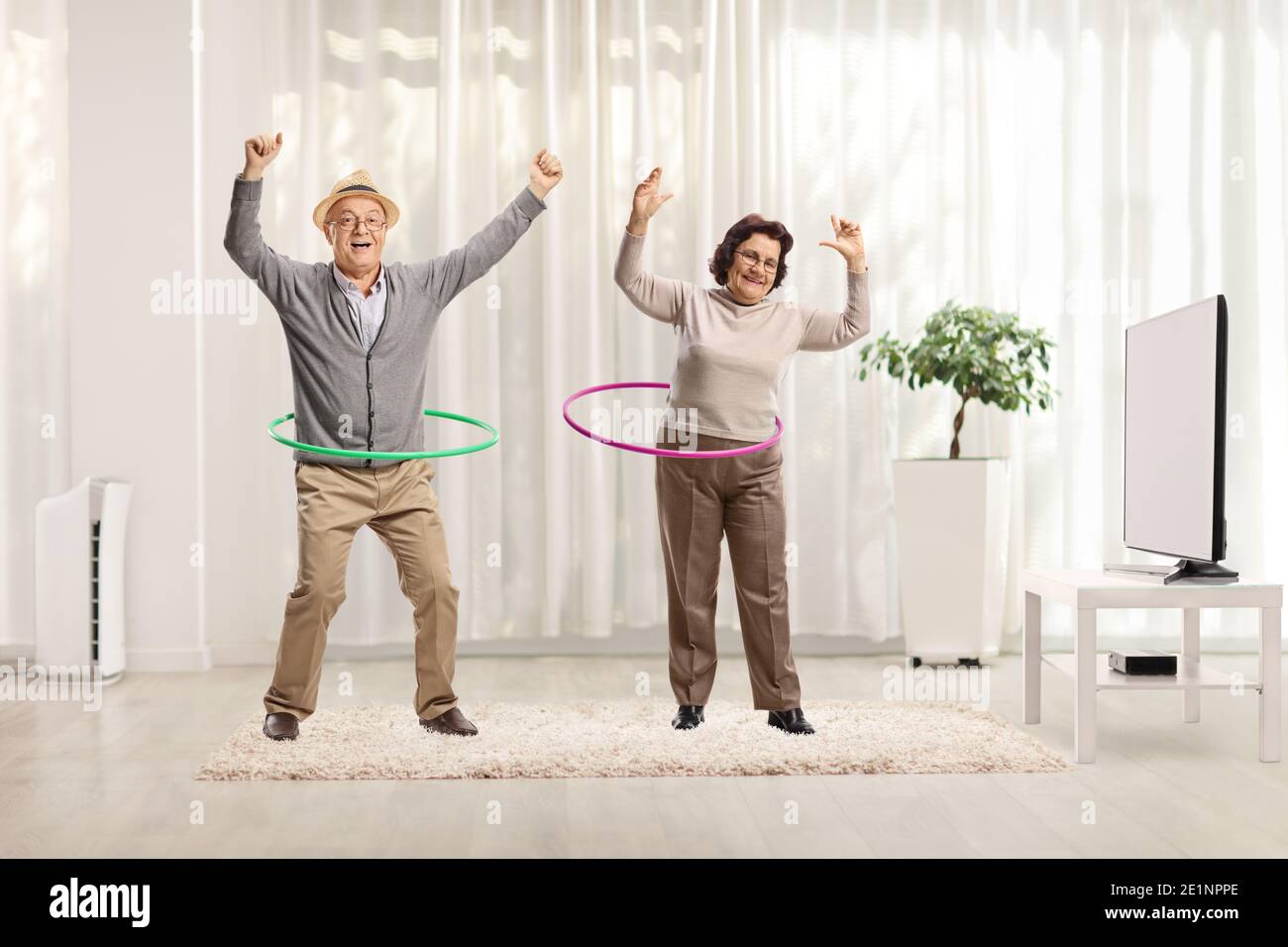 Elderly couple spinning hula hoops at home Stock Photo
