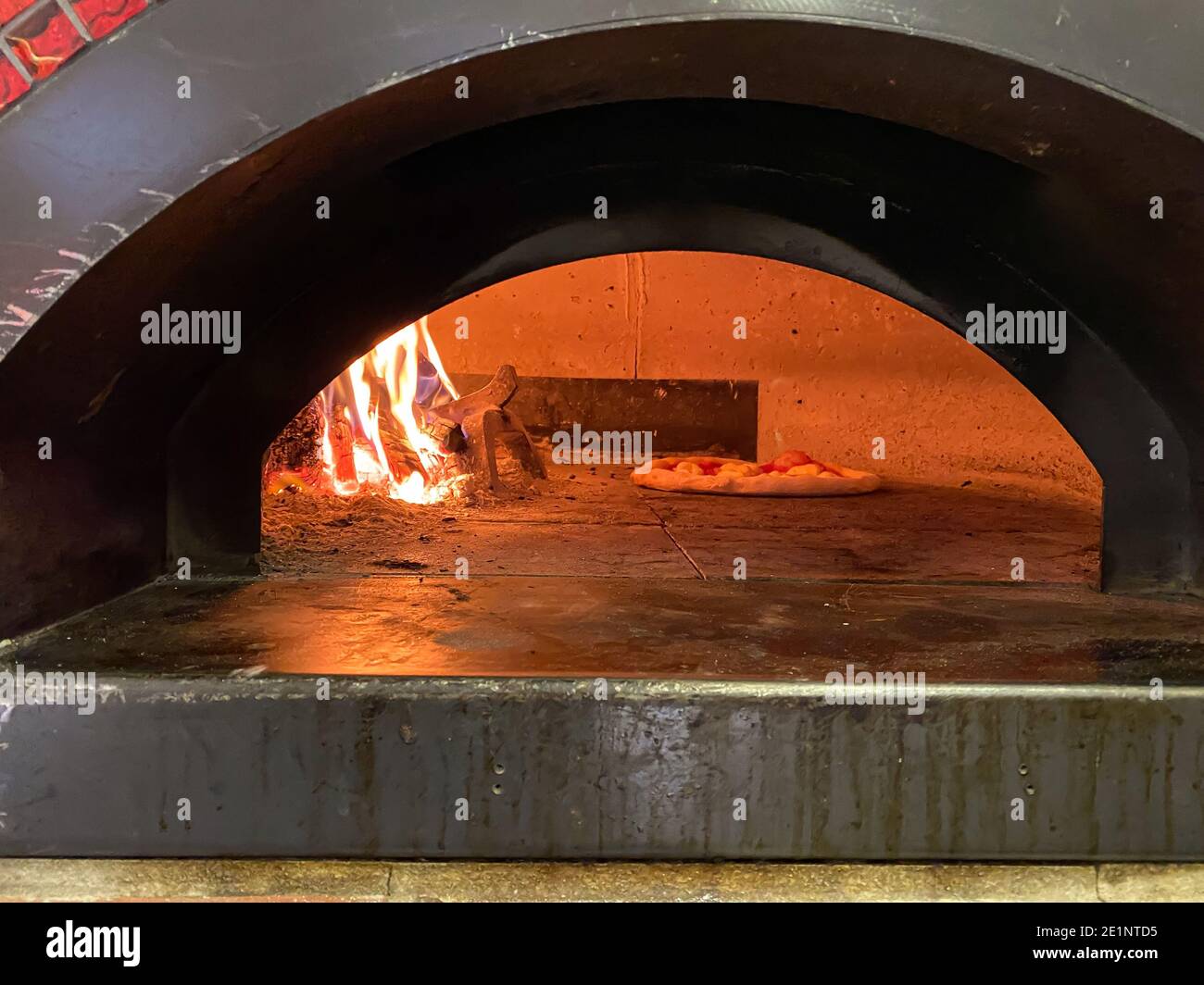 Baking oven, fireplace in the middle next to rising dough pizza, Italian traditional dish Stock Photo