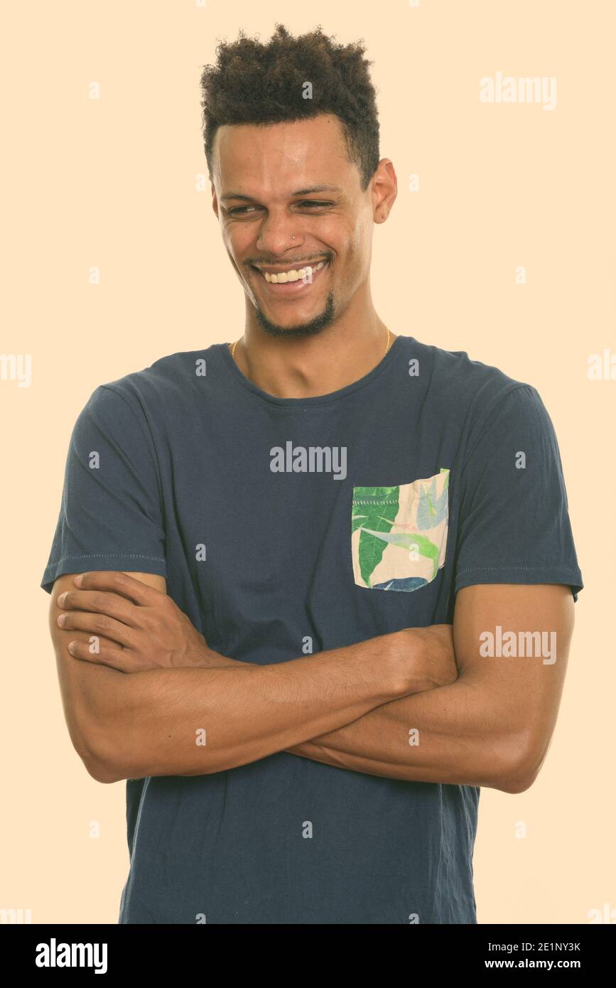 Studio shot of young happy African man smiling while thinking with arms ...