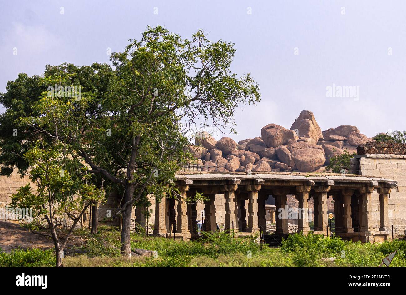 Hampi, Karnataka, India - November 5, 2013: Badavilinga Temple in its natural environment of green vegetation and huge brown boulders. Small ruinous b Stock Photo