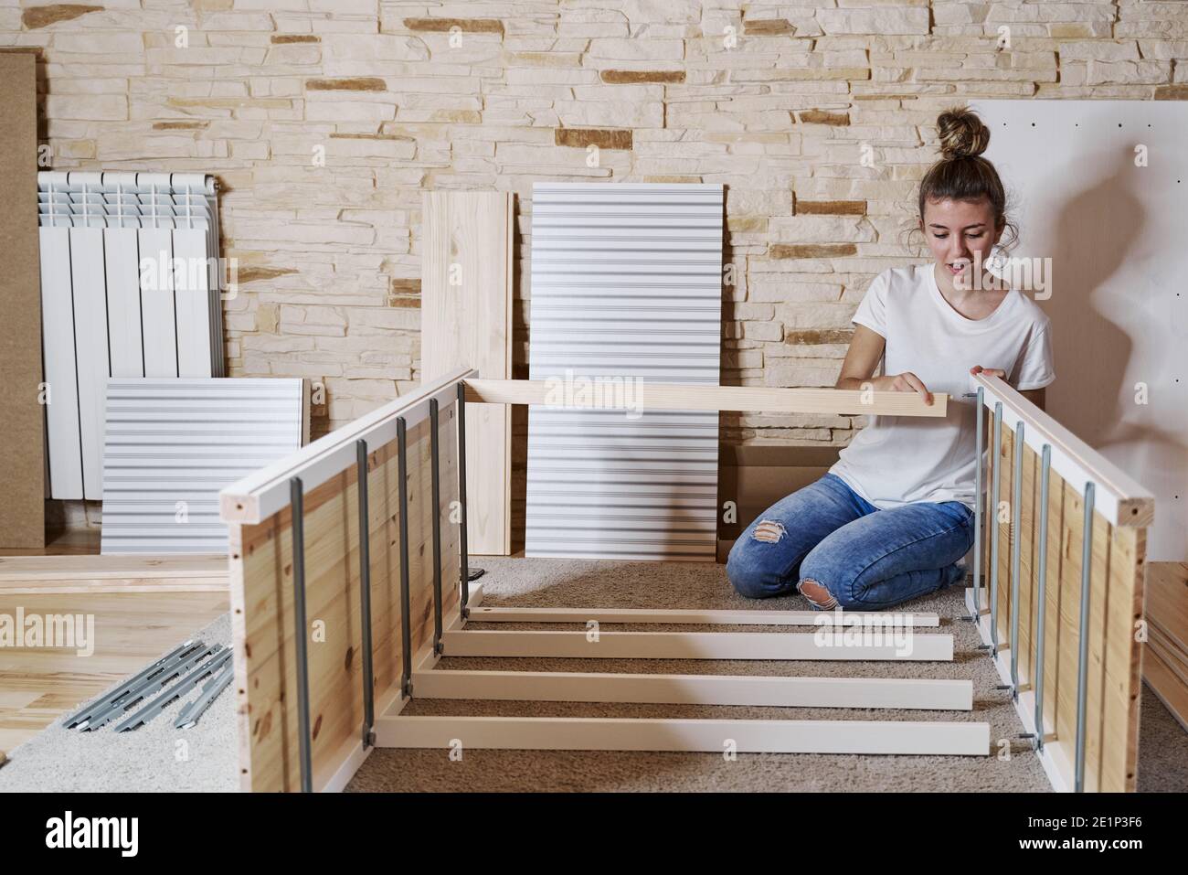Front view of a young blonde girl screwing a screw with a screwdriver in a  strip of a furniture assembling by herself a wardrobe of wood. Horizontal p  Stock Photo - Alamy