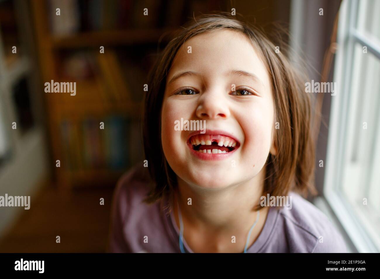 An adorable girl with bright eyes proudly displays a missing tooth Stock Photo