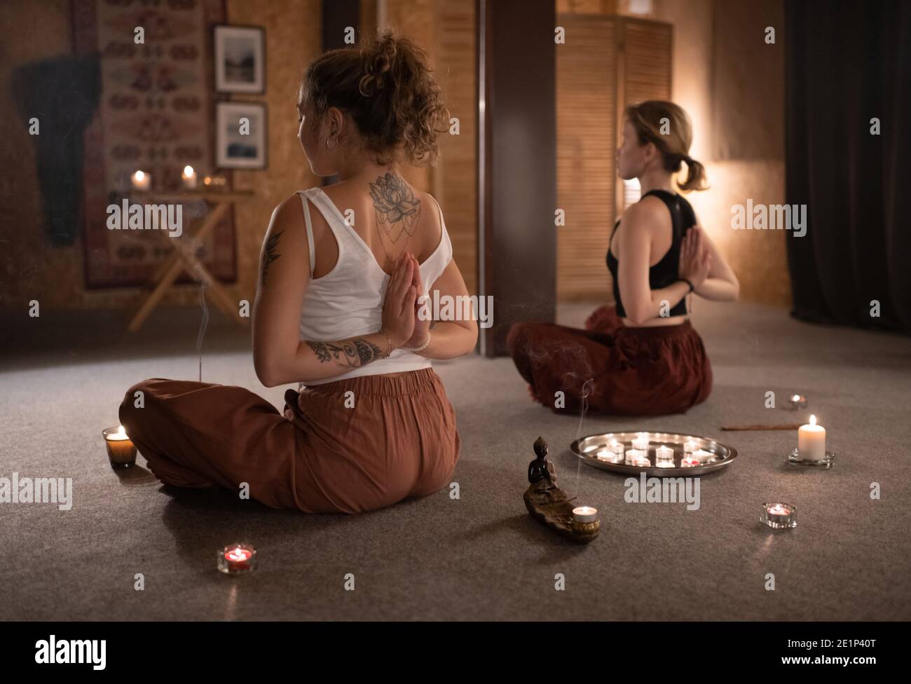 Slim women with hands clasped behind back sitting near candles and