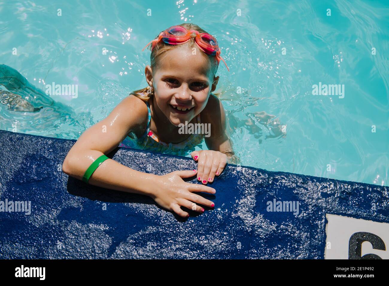 Little Girl holding onto side of the pool looking up and smiling Stock ...