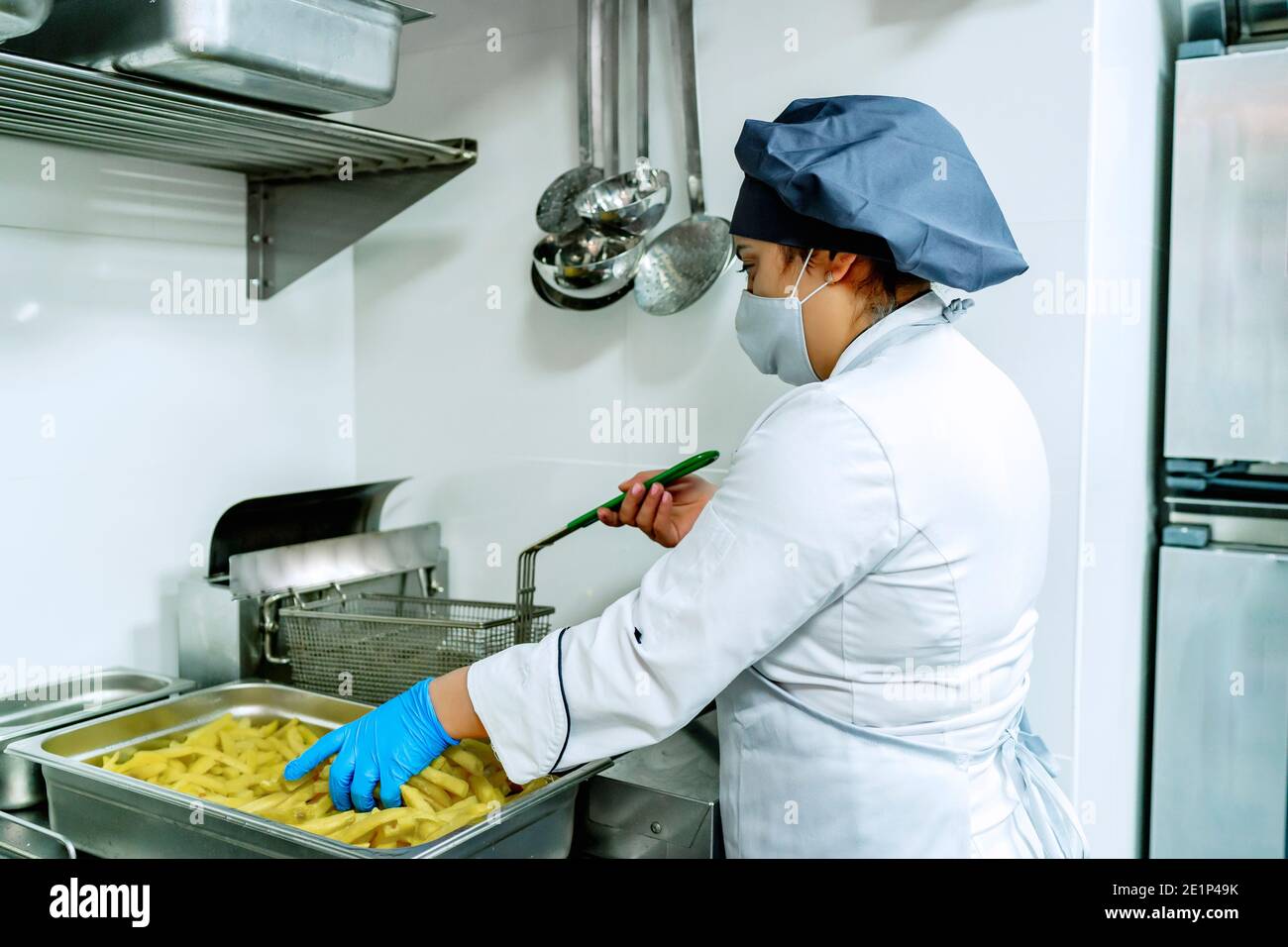 cook in her restaurant frying potatoes Stock Photo - Alamy