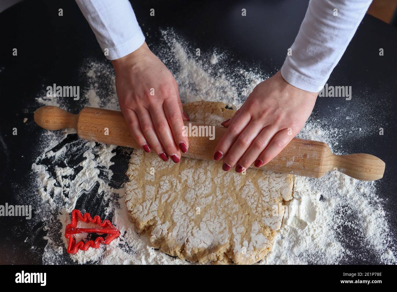 Female hands with a wooden rolling pin roll out the cookie dough on the  kitchen table covered with flour. Homemade prepare and decoration food  concept Stock Photo - Alamy