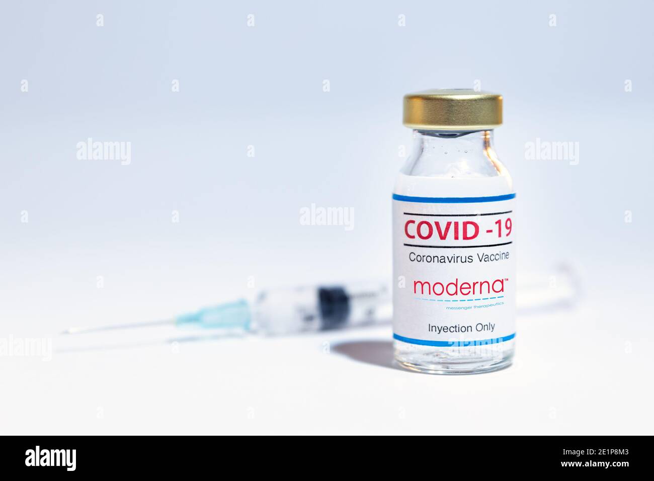 Bottle of coronavirus vaccine with the Moderna logo and syringe background. Stock Photo