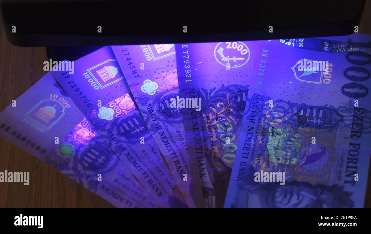 Warsaw, Poland 01.01.2021 10000 hungarian forint banknote being tested for counterfeiting under the UV lamp. anti-counterfeiting technology used to prevent fraud and money malversation. High quality photo Stock Photo