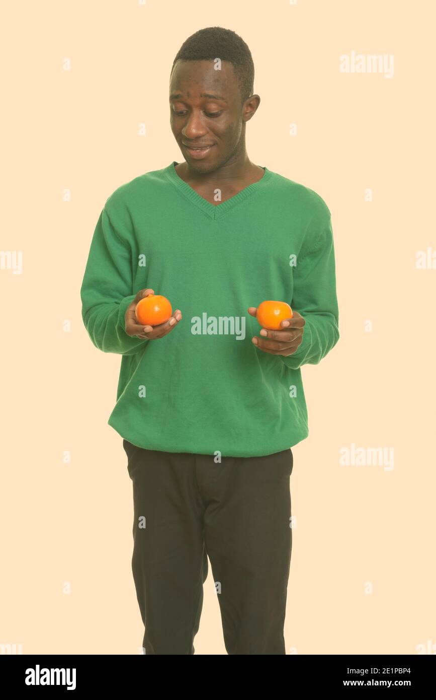Young happy African man smiling and holding two oranges Stock Photo - Alamy