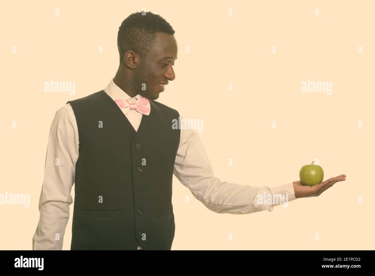 Young happy African waiter smiling and holding green apple Stock Photo ...
