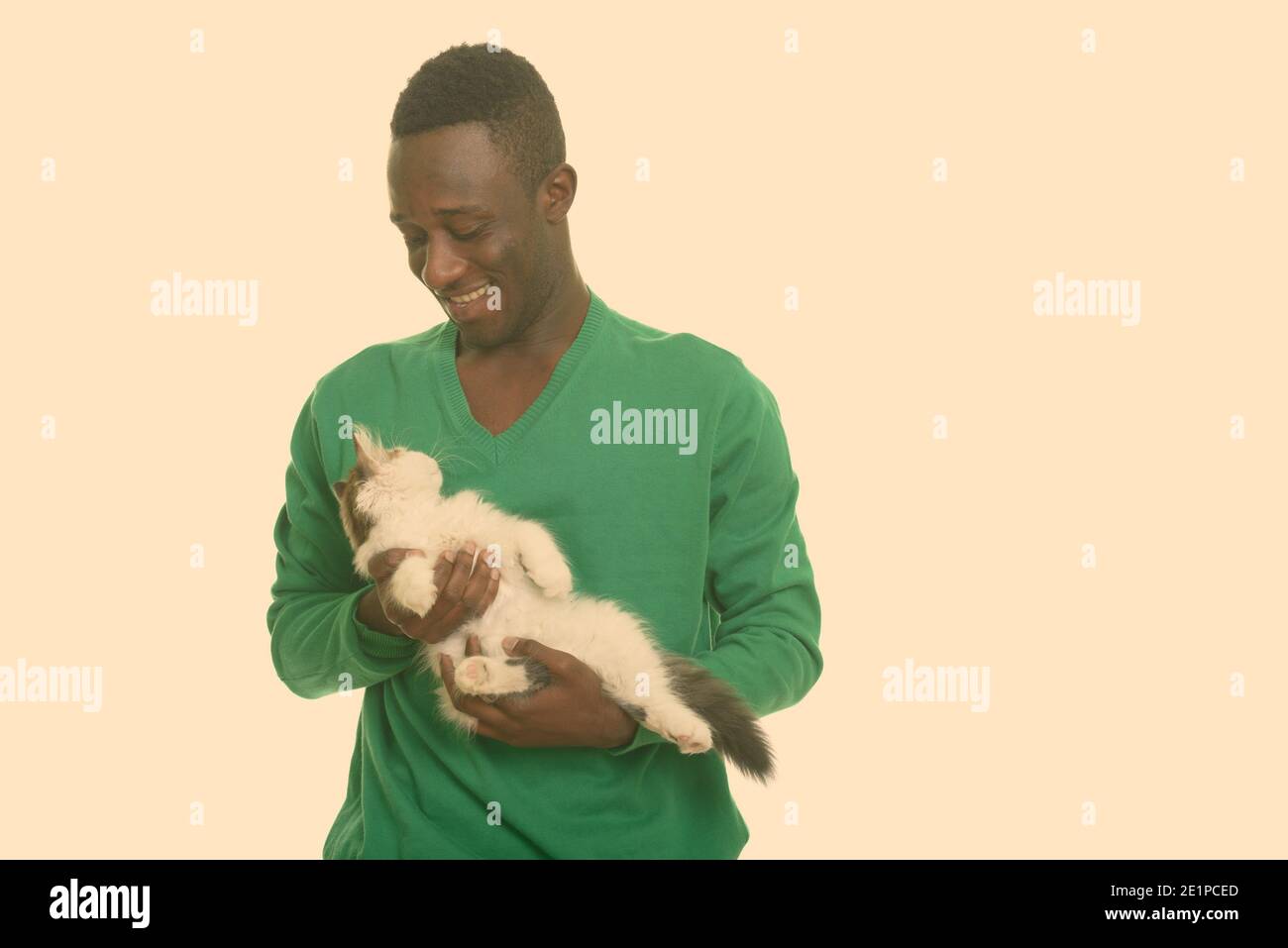Young happy African man smiling and holding and looking at cute cat Stock Photo