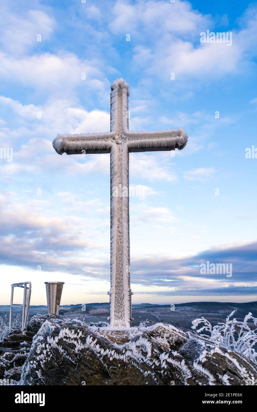 Summit Cross heavily freezed with snow and ice at cloudy blue sky Stock Photo