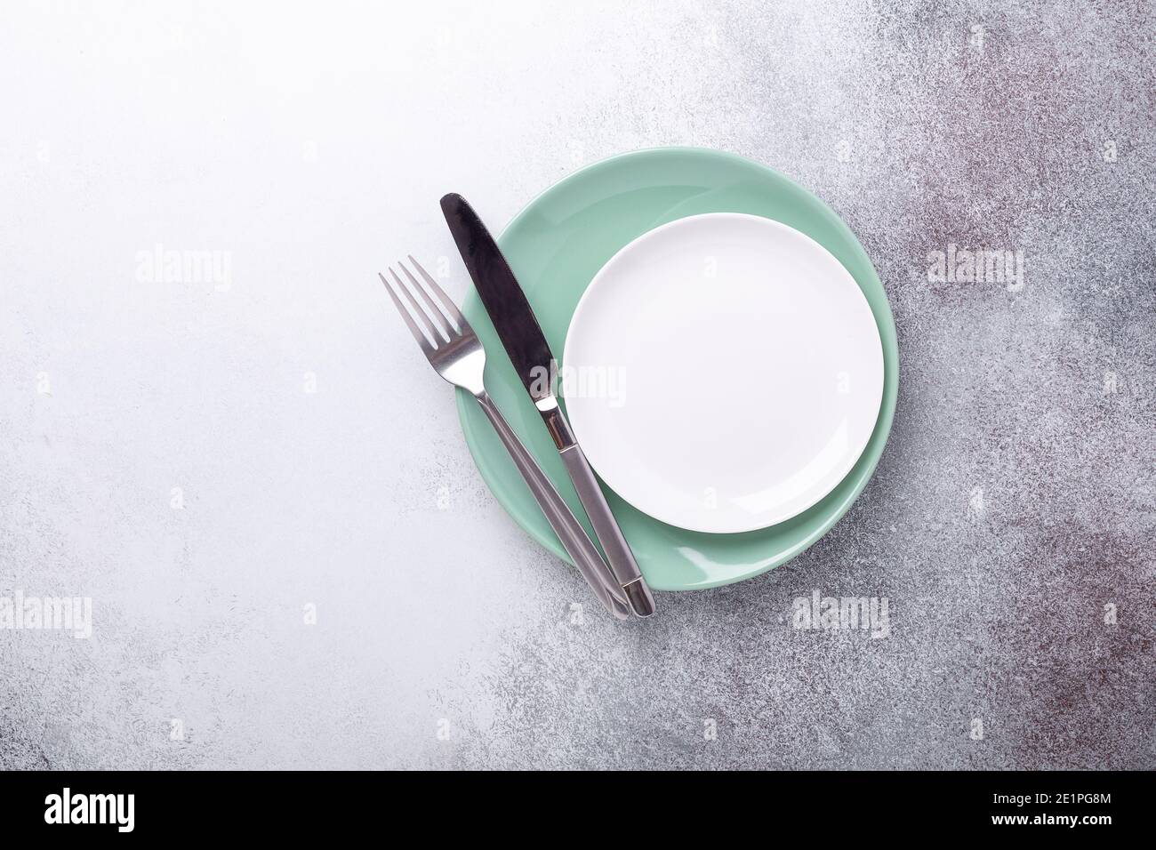 Empty mint and white plates, knife and fork on stone background Copy space Top view - Image Stock Photo