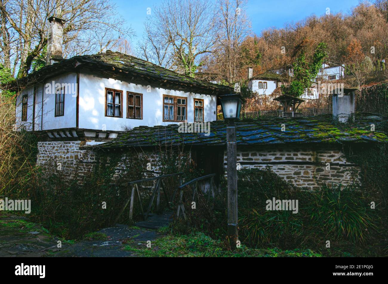 Traditional Bulgarian house in revival village of Bozhentsi during wintertime with moss on stone roof. Stock Photo