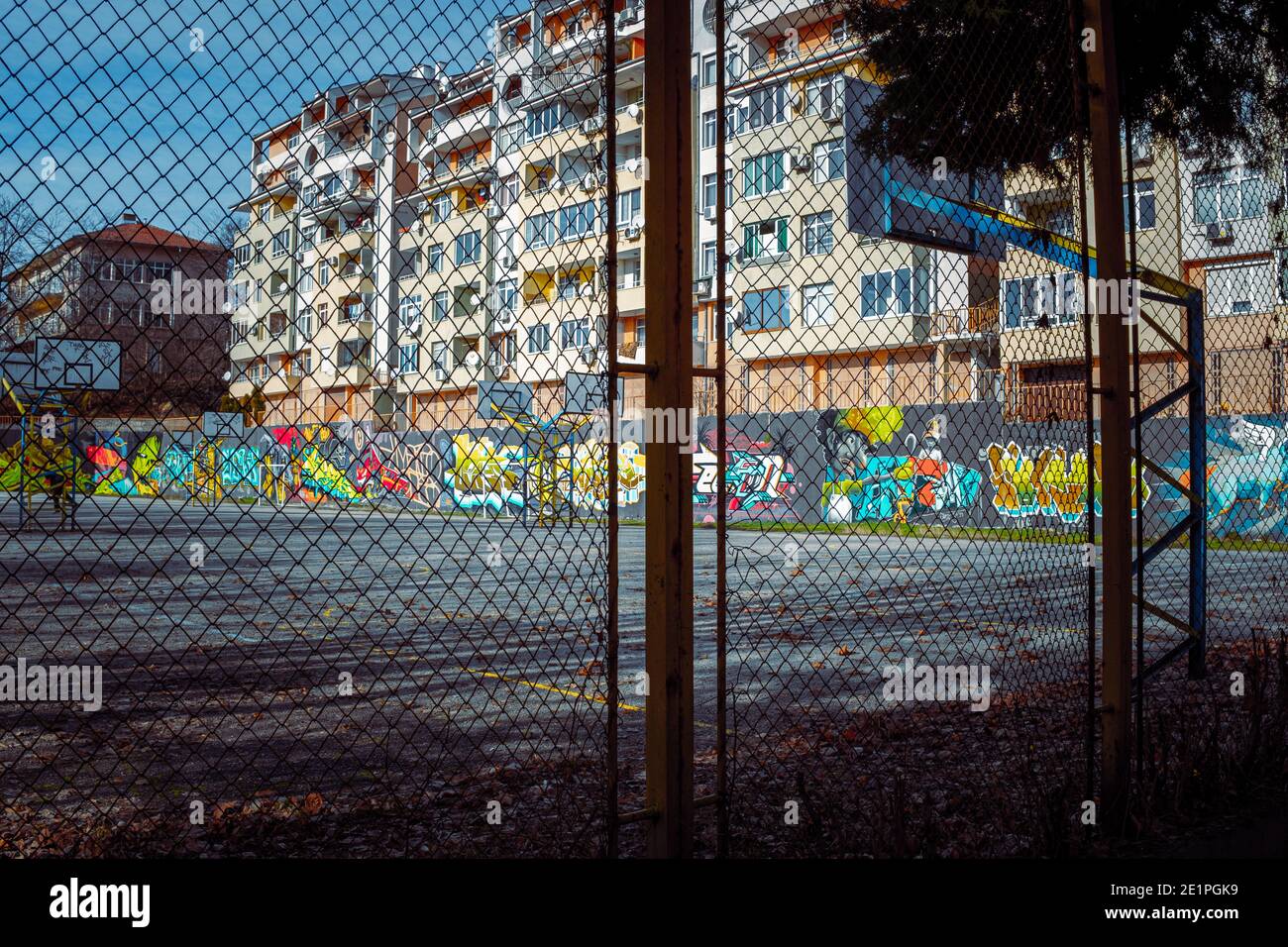Looking through rusty fence into deserted urban playground area in city of Veliko Tarnovo with street art painted and decorating walls. Stock Photo