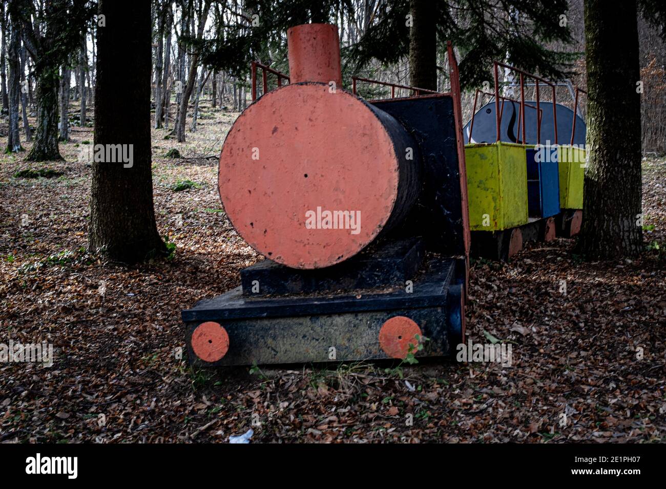 Old,deserted children's playground in wooded area during wintertime with fallen dead leaves Stock Photo