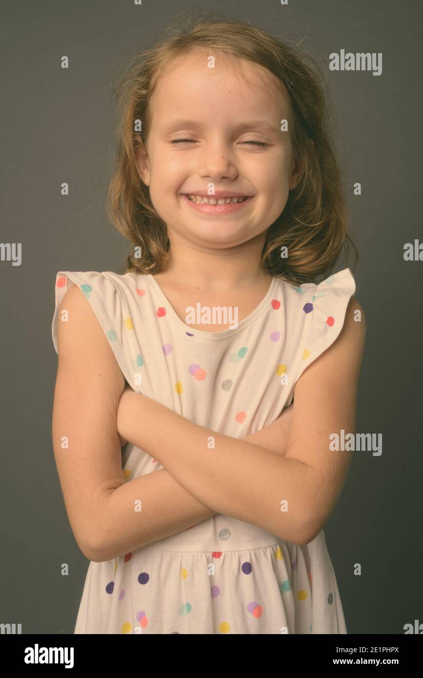 Cute young girl with blond hair against gray background Stock Photo