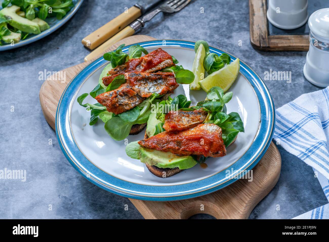 Sardines in tomato sauce with avocado and lambs lettuce on toast Stock