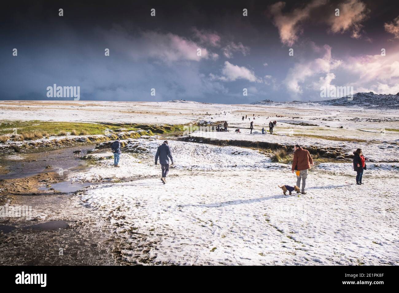 People enjoying walking in the snow on the wild rugged Rough Tor on Bodmin Moor in Cornwall. Stock Photo