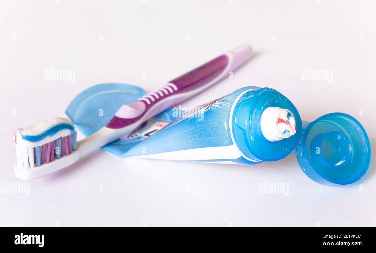 Multi-colored toothpaste on a toothbrush and tube. Close-up. Stock Photo