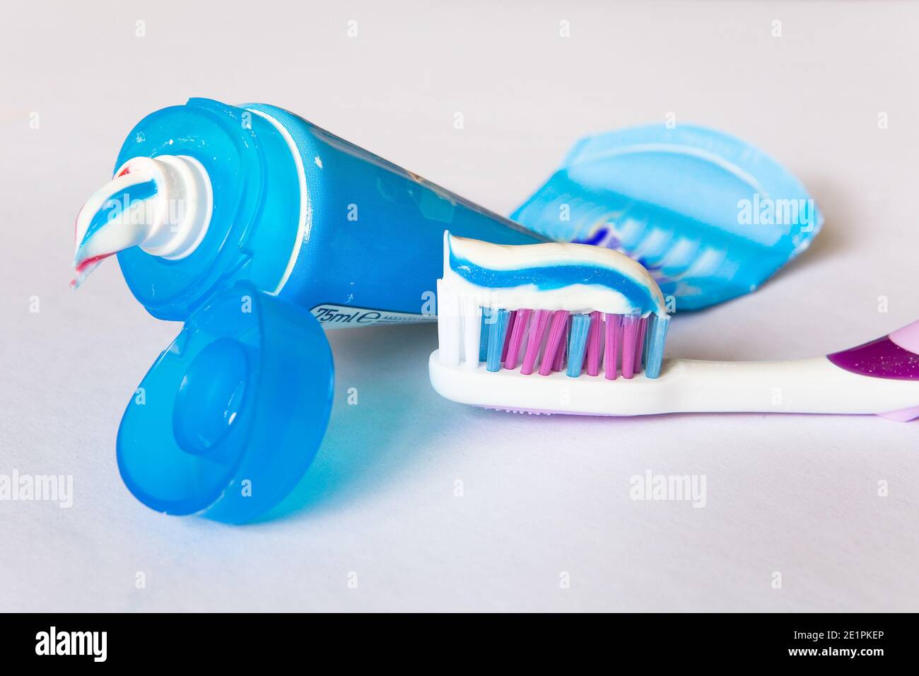 Multi-colored toothpaste on a toothbrush and tube. Close-up. Stock Photo