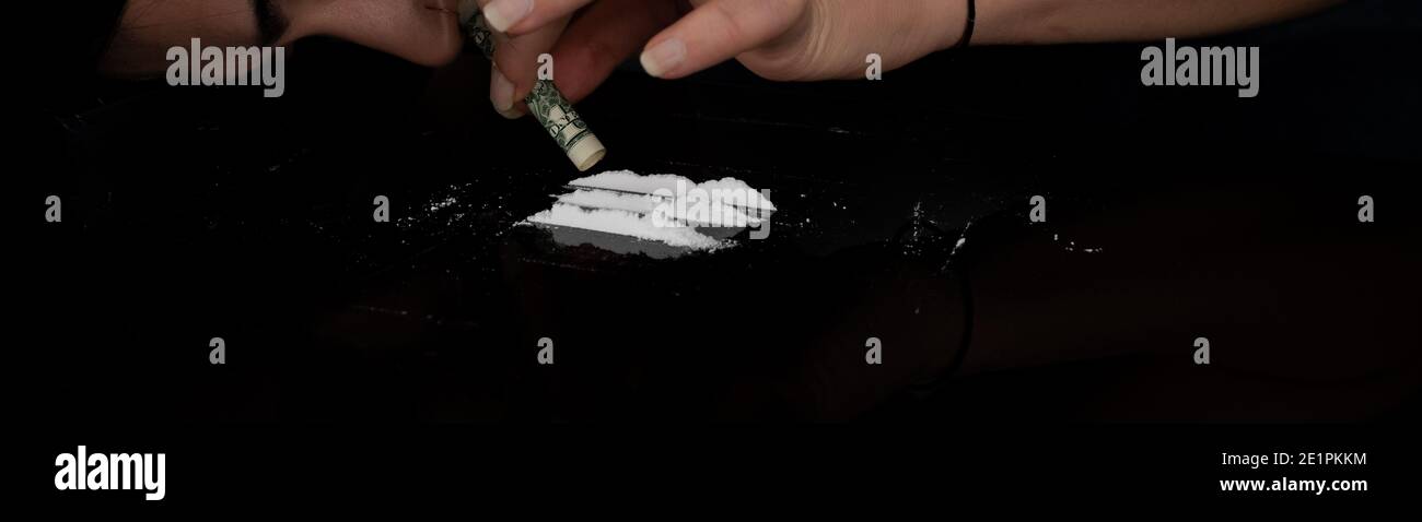 Drug addict woman snorting cocaine powder with rolled dollar banknote. Narcotics concept. Close-up macro shot. Panoramic shot. Panorama banner. High r Stock Photo