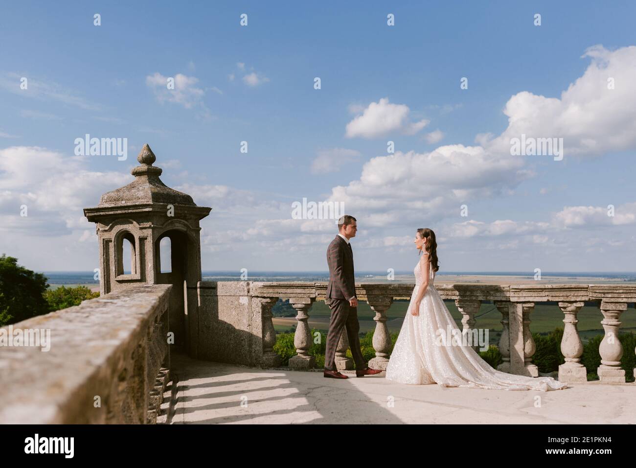 The bride and groom go to meet each other on the terrace of the palace against the sky Stock Photo