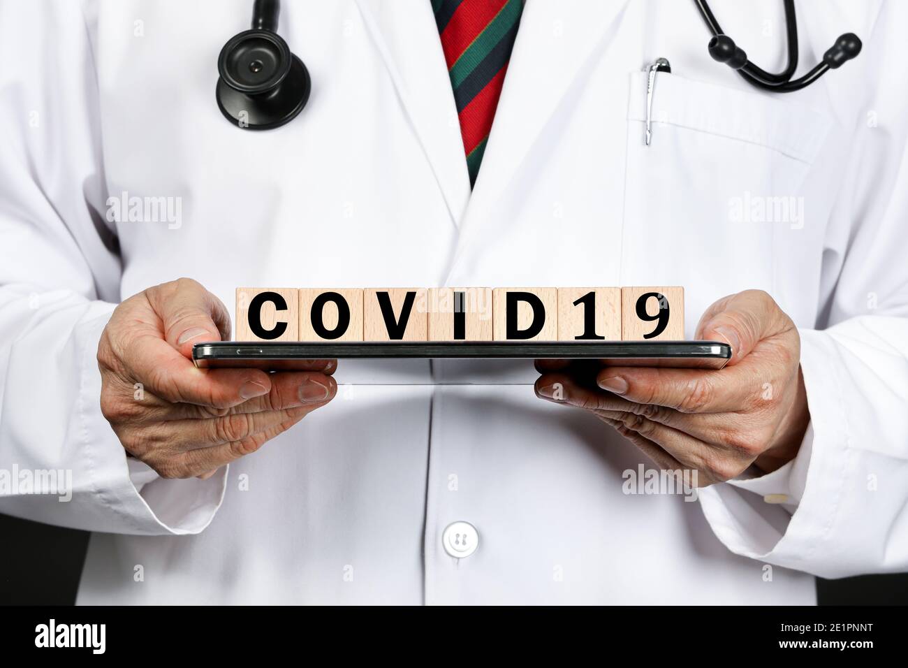 A male doctor in white coat showing letter blocks spelling covid19, as a warning for corona virus epidermic which has recently official named covid-19 Stock Photo