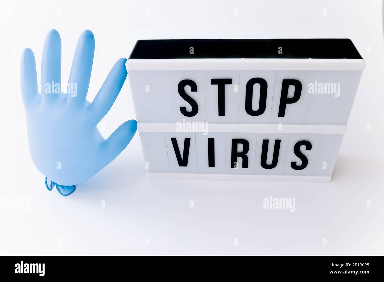 Epidemic and healthcare concept - close up of lightbox with Stop corona virus caution words and protective glove balloon Stock Photo