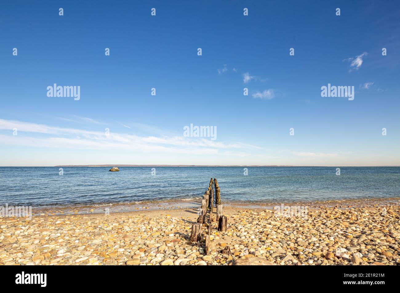 Old pilings on a rocky beach with old retaining wall in East Hampton, NY Stock Photo