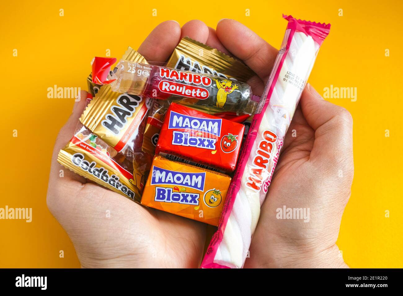 Tambov, Russian Federation - January 06, 2021 Woman palms full of Haribo candies. Yellow background. Stock Photo