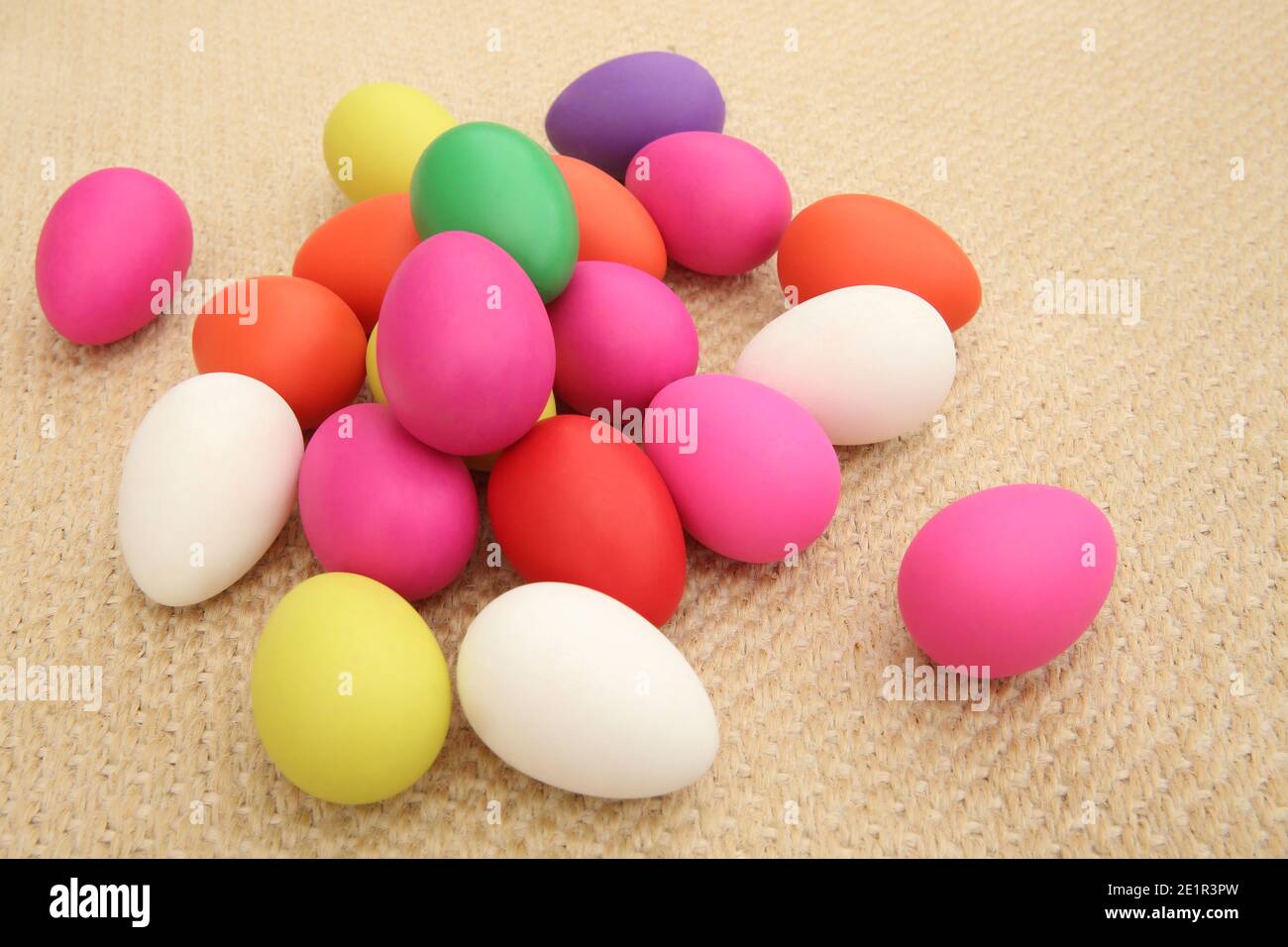 Multi colored easter eggs against a natural beige woven matt background. Stock Photo