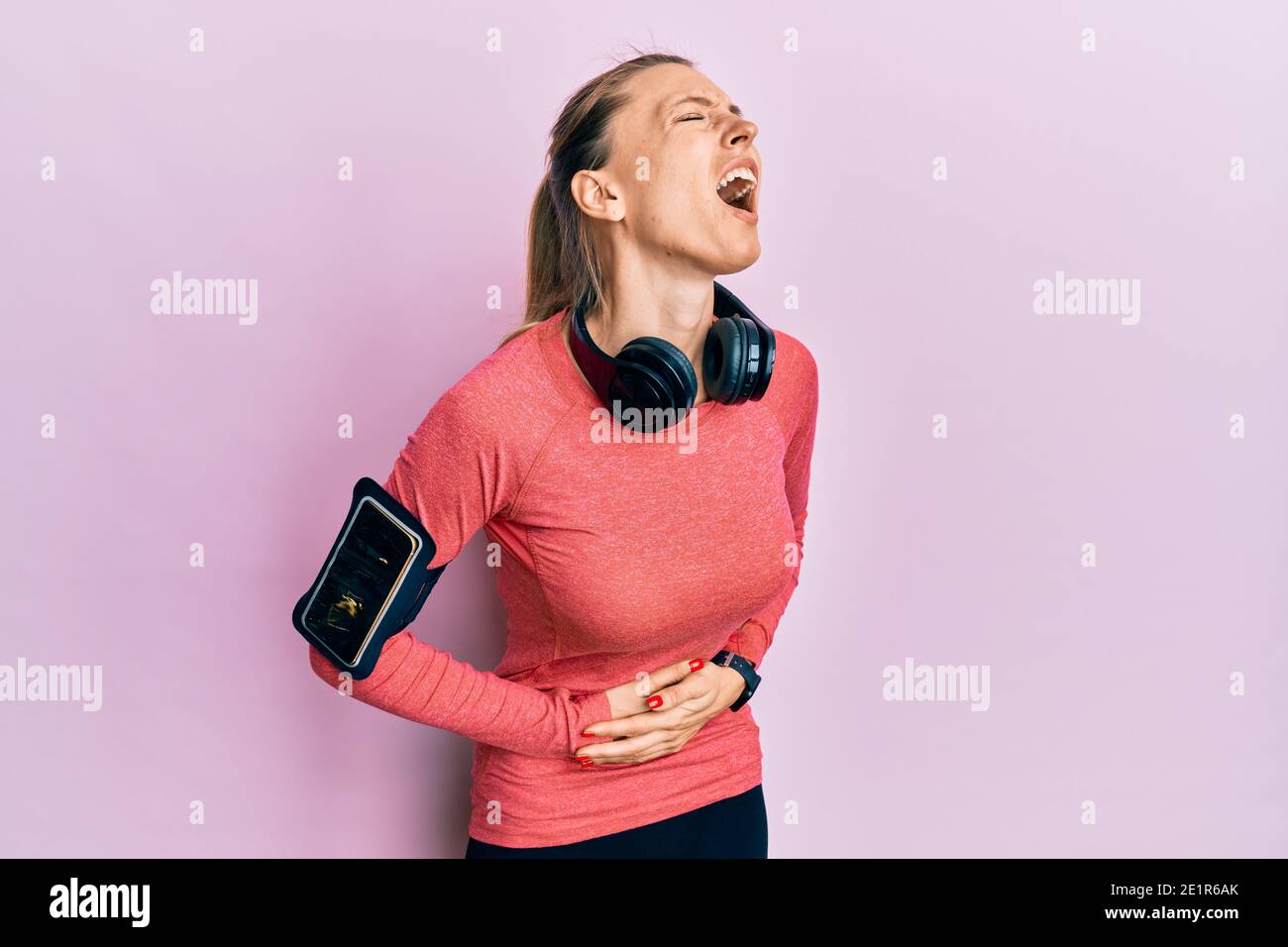 Beautiful caucasian woman wearing sportswear and arm band with hand on