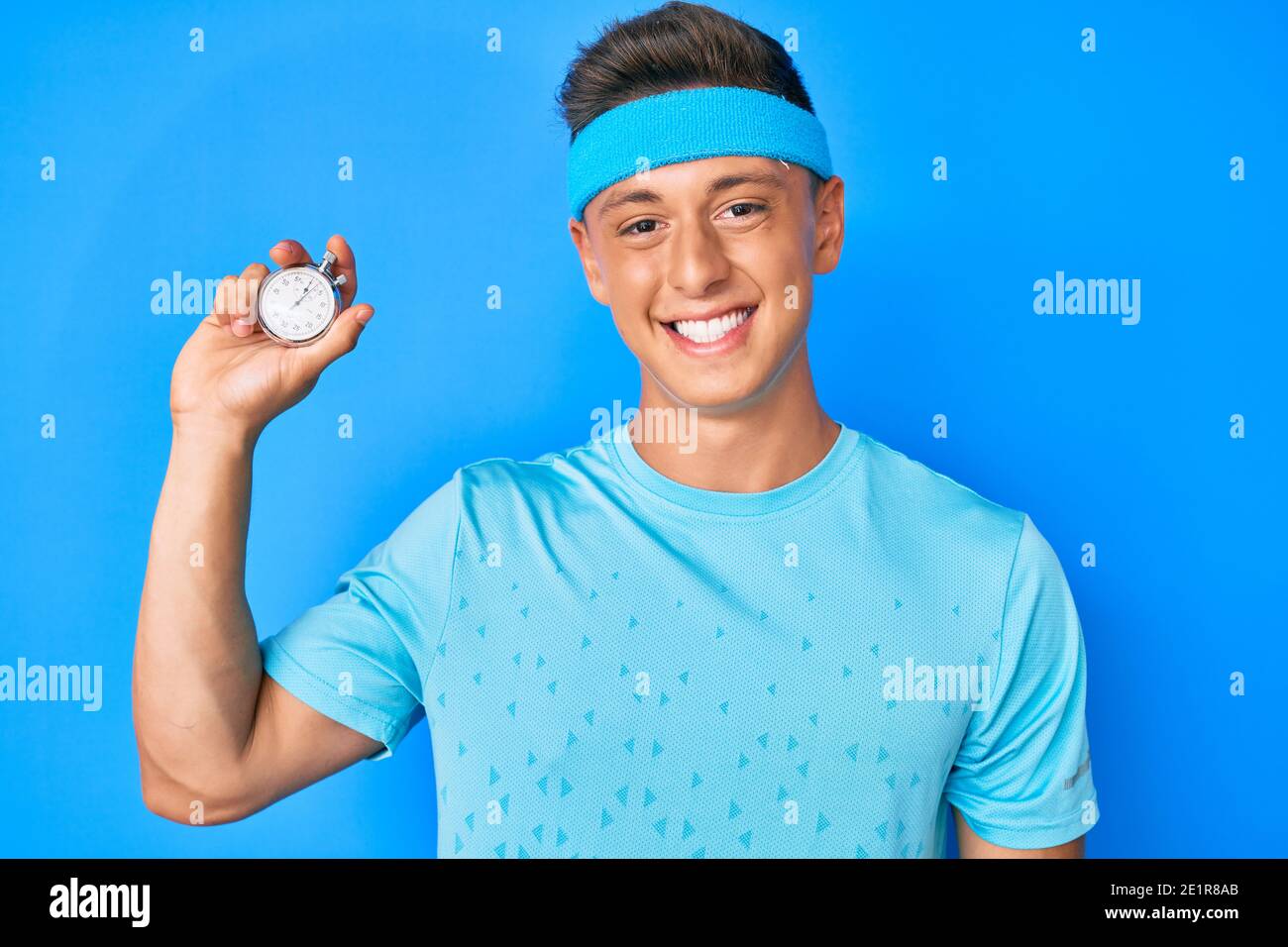 Young hispanic boy holding stopwatch looking positive and happy ...