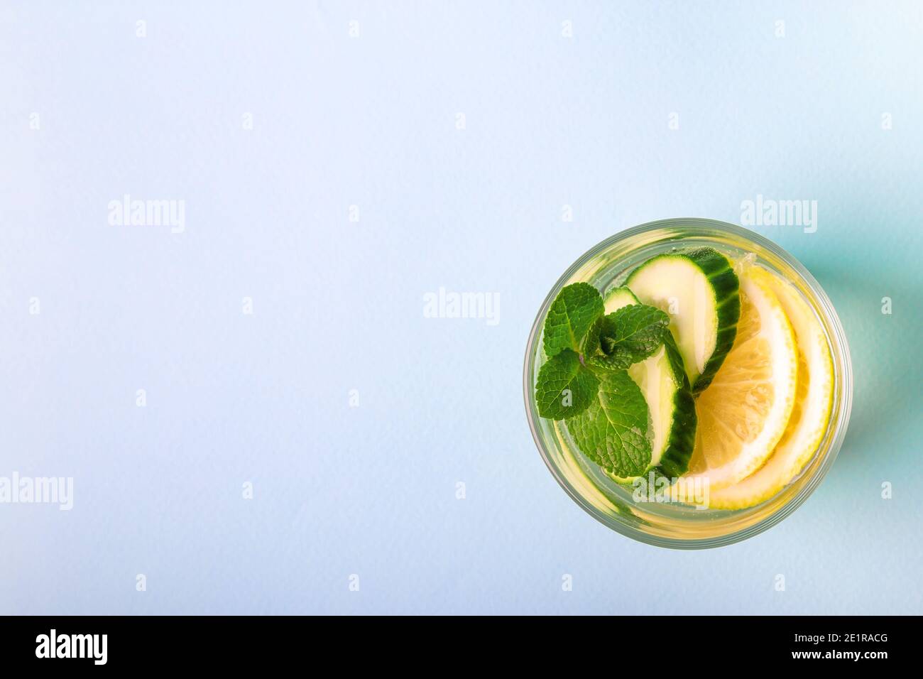 Sassy water for detox infused with lemon, cucumber and mint in glass on light blue background. Top view. Healthy lifestyle concept. Space for text. Stock Photo