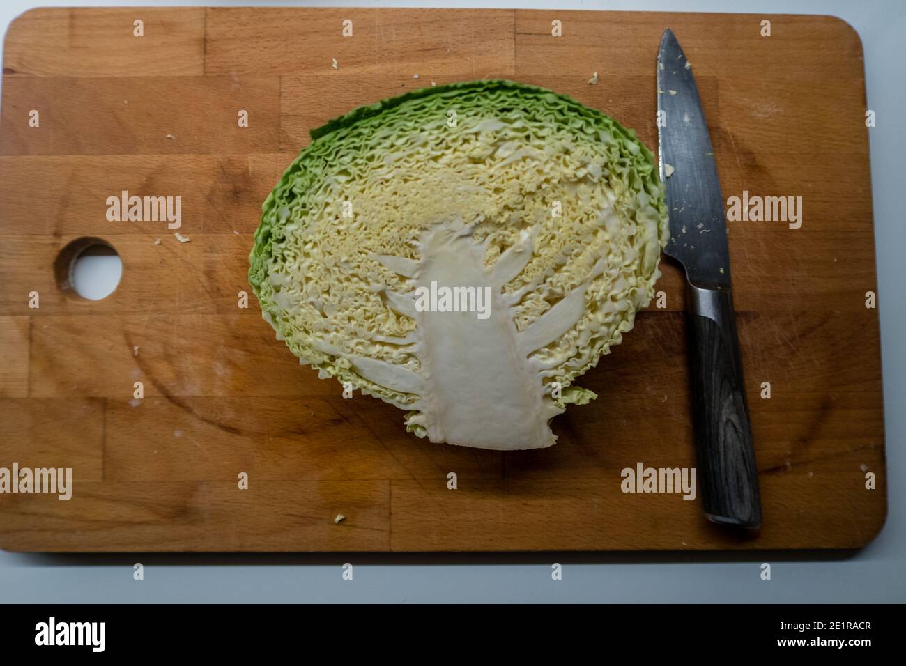 A cabbage cut in a half and placed on a chopping board, ready to be
