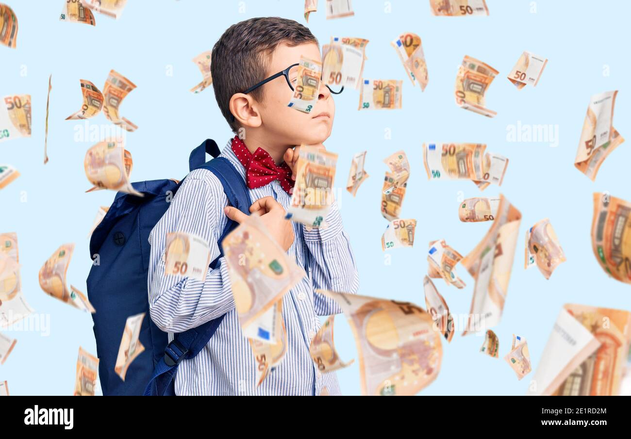 Cute blond kid wearing nerd bow tie and backpack serious face thinking about question with hand on chin, thoughtful about confusing idea Stock Photo