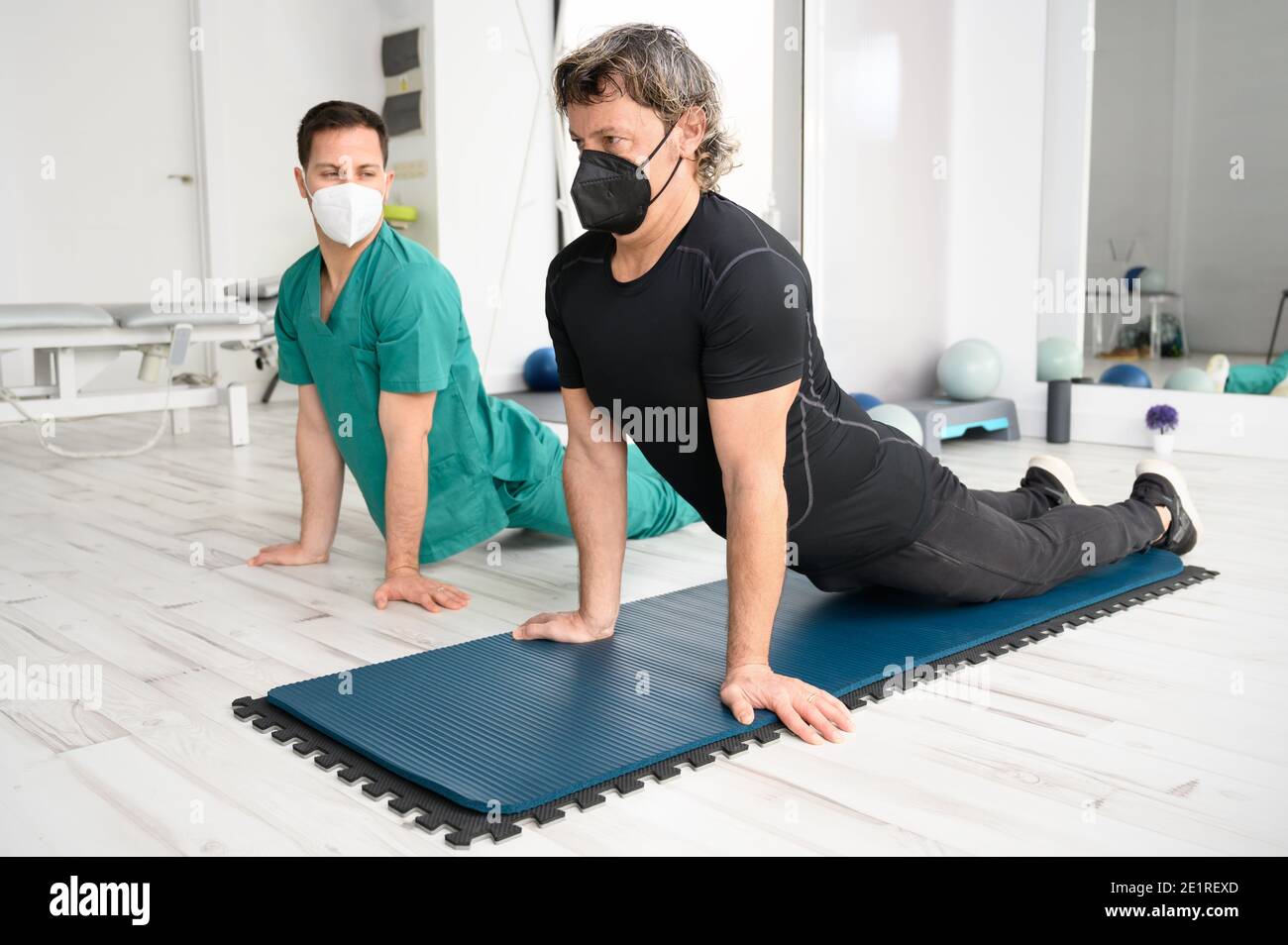 Physiotherapist assisting man in performing exercise on mat. High quality photo Stock Photo