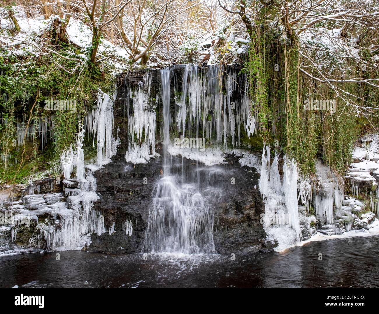 Snow and Ice covered waterfall flowing into the Linhouse Water, Almondell and Calderwood Country Park, West Lothian, Scotland Stock Photo