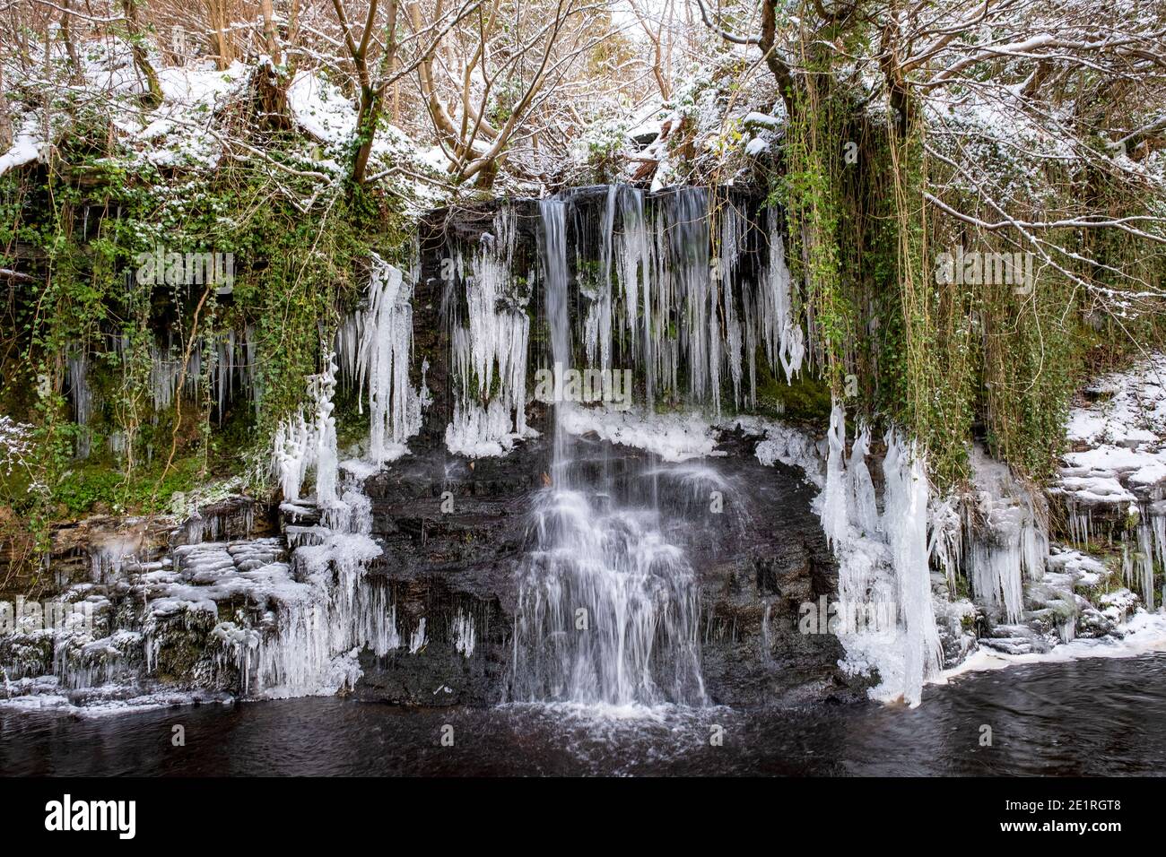 Snow and Ice covered waterfall flowing into the Linhouse Water, Almondell and Calderwood Country Park, West Lothian, Scotland Stock Photo