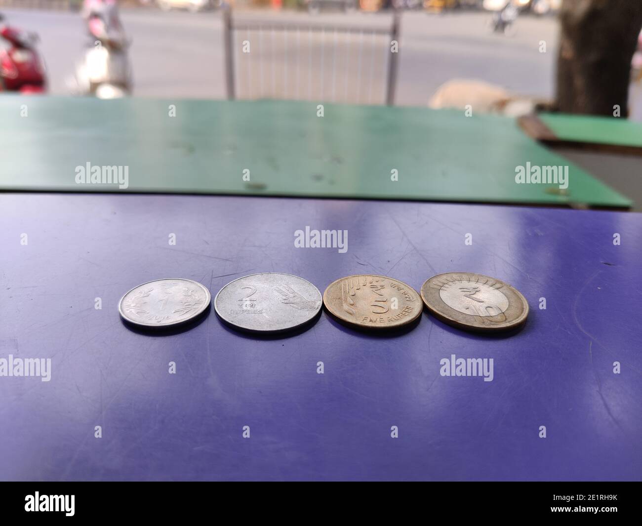 New designed Indian currency coins of rupees one, two, five, and ten kept  on blue background closeup shot with street road background Stock Photo -  Alamy