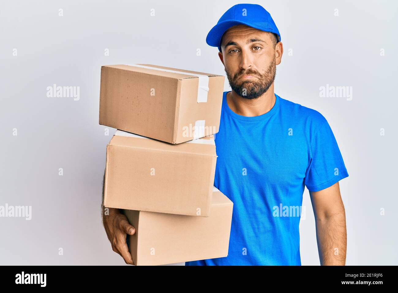 Handsome man with beard wearing courier uniform holding delivery ...
