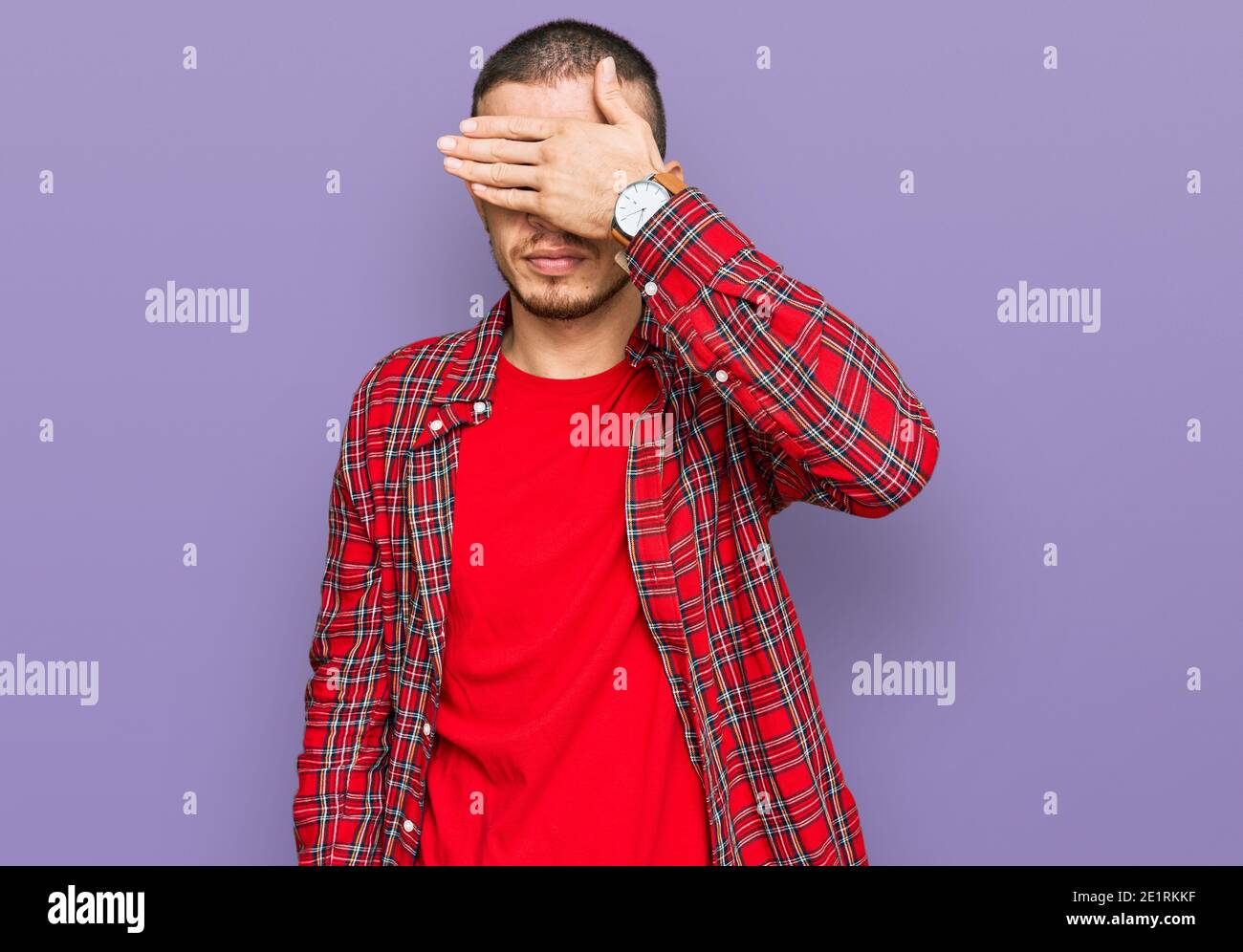 Hispanic young man wearing casual clothes covering eyes with hand ...