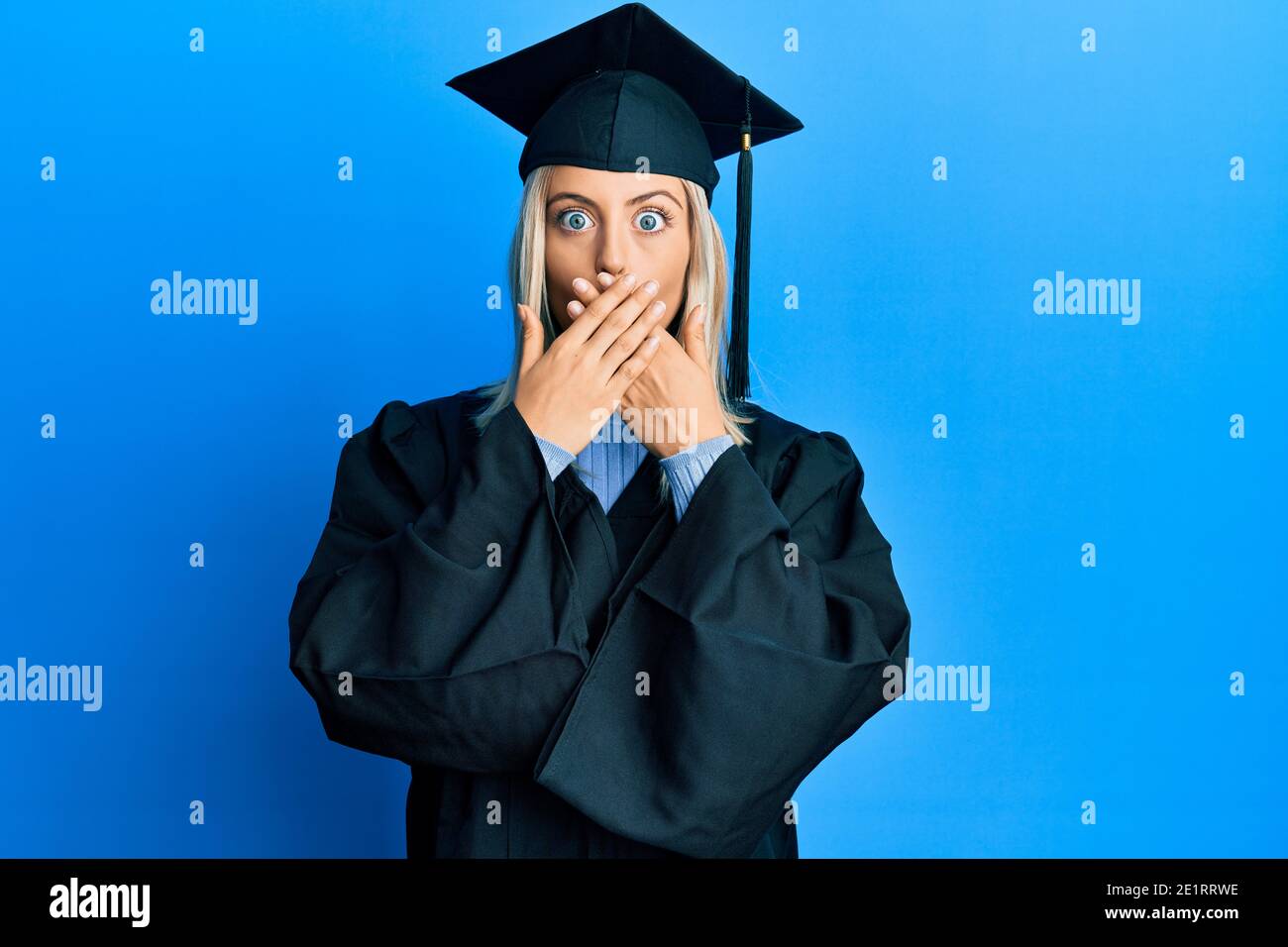 Beautiful blonde woman wearing graduation cap and ceremony robe shocked ...