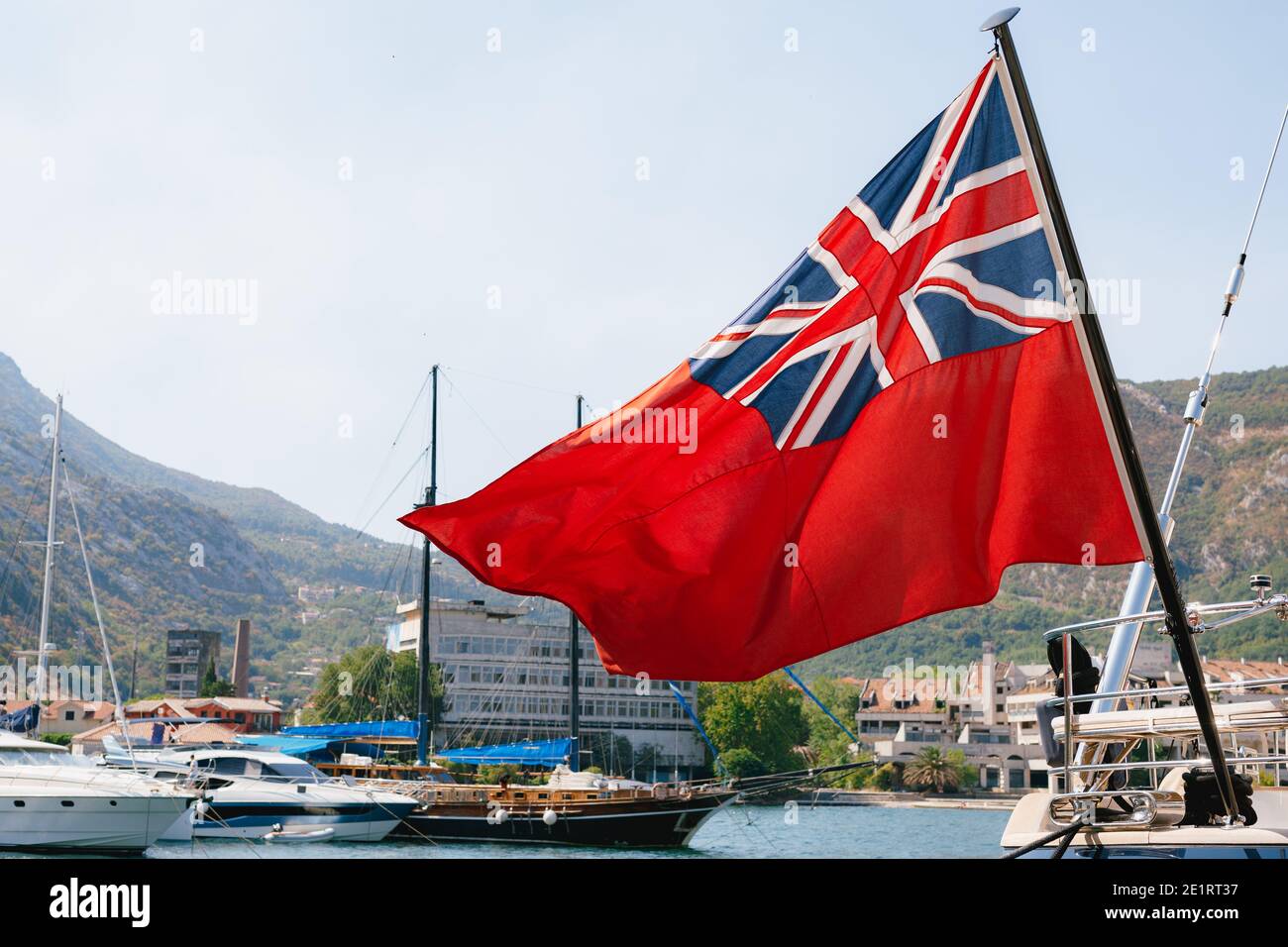 Close-up of the British Red Ensign aboard a ship with ships and mountains  in the background. Red flag with the first version of Union Jack in the  Stock Photo - Alamy