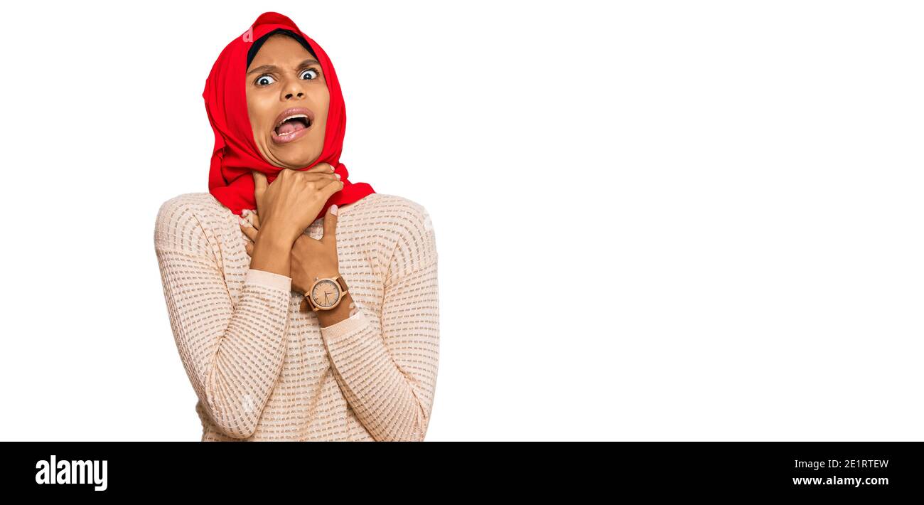 Young african american woman wearing traditional islamic hijab scarf shouting suffocate because painful strangle. health problem. asphyxiate and suici Stock Photo