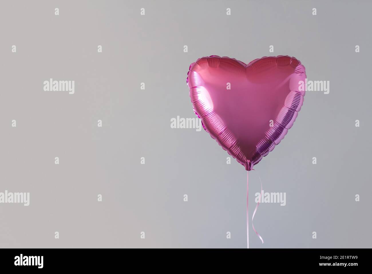 Pink balloon in the form of a heart against the background of a gray wall copy space. Stock Photo