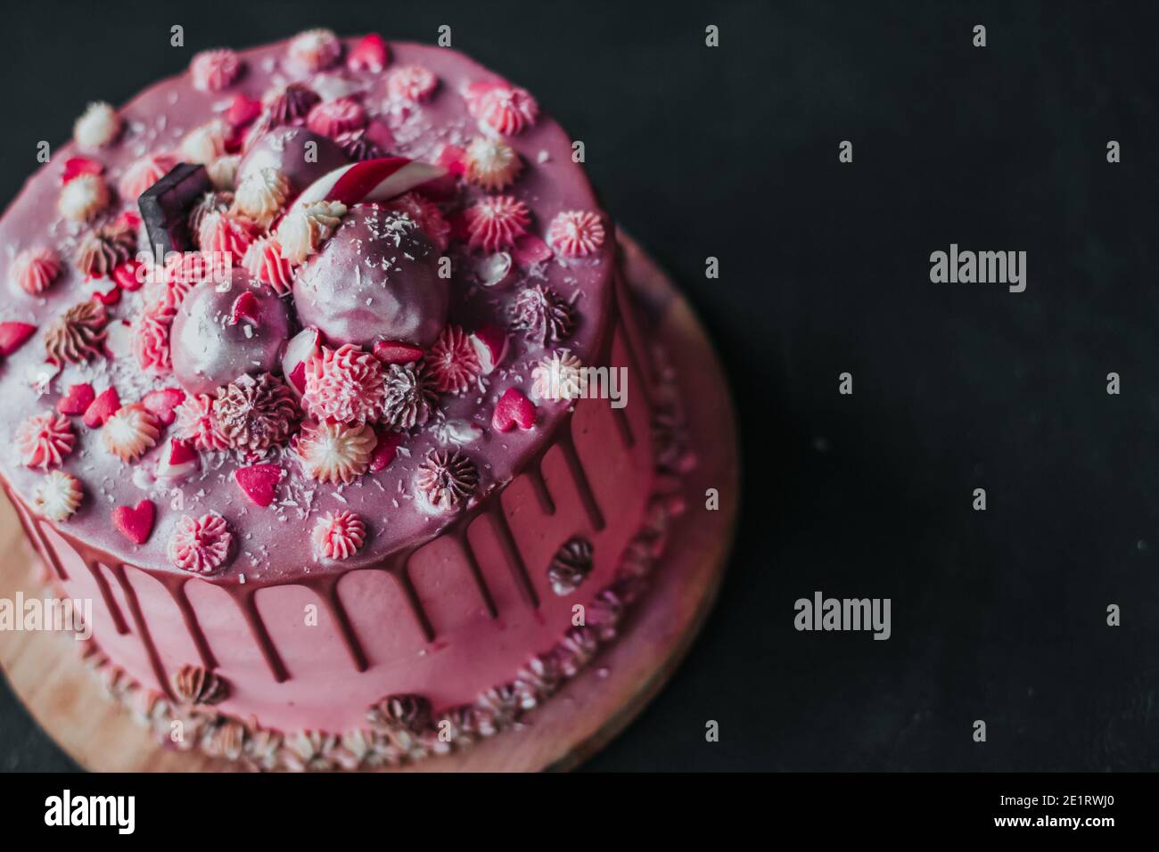 Birthday cake with pink cream and chocolate icing, sprinkled with hearts and sweets. Homemade cake copy space Stock Photo